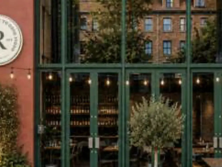 Route Café façade with deep green window frames, climbing greenery, planters and warm string lighting